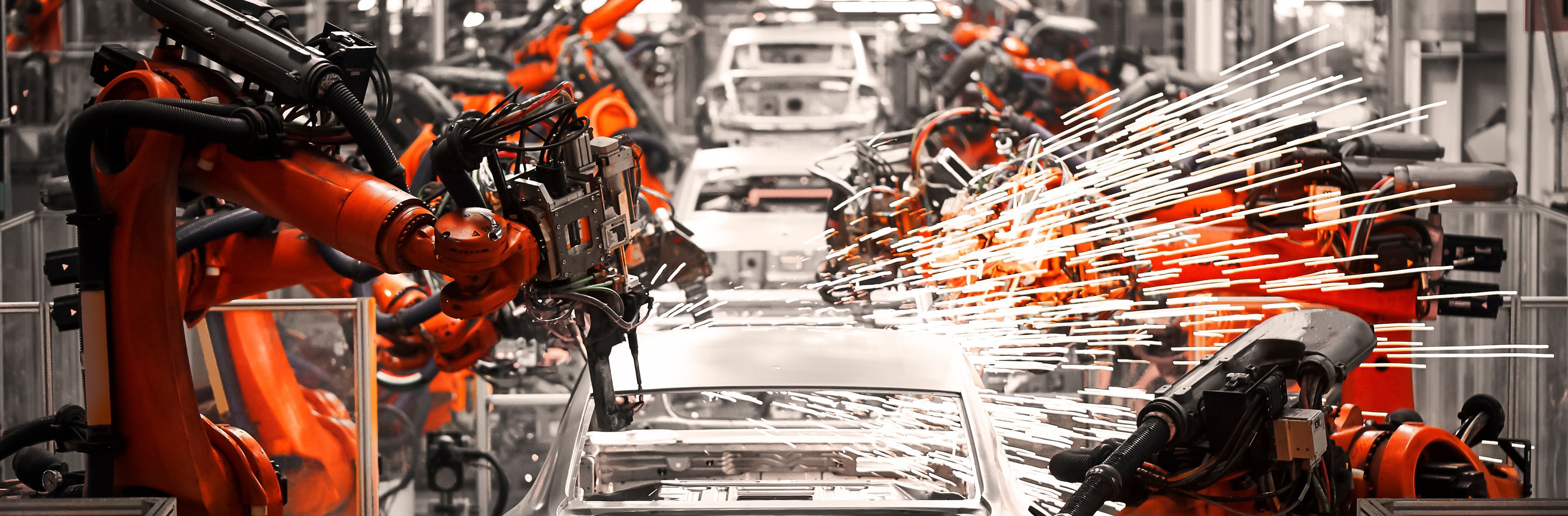 Robotic arms in a automotive production facility. Many sparks are flying around.